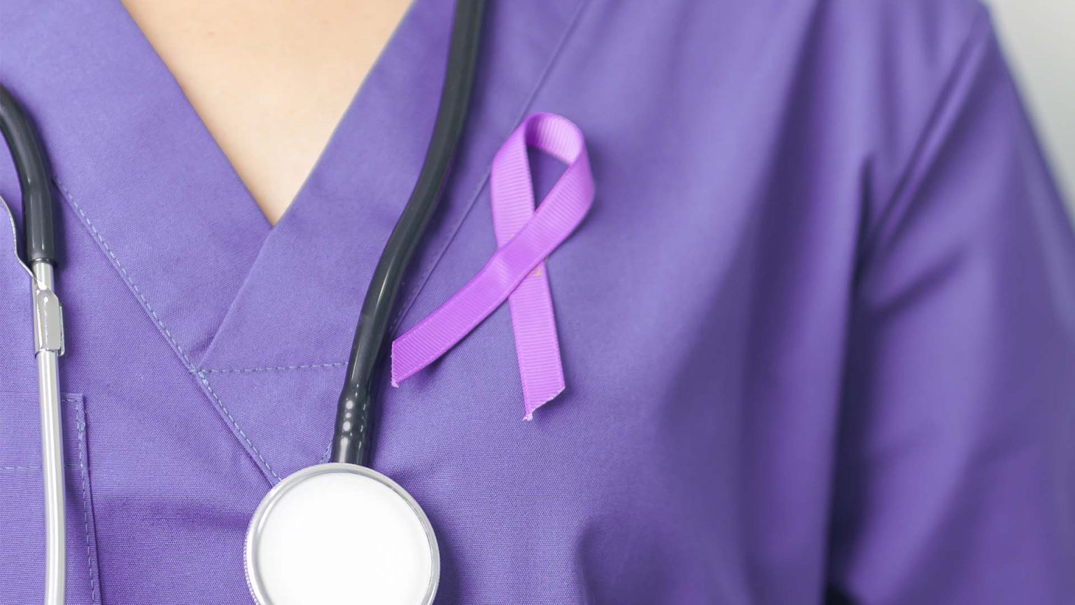 Doctor wearing scrubs with purple ribbon for epilepsy awareness.