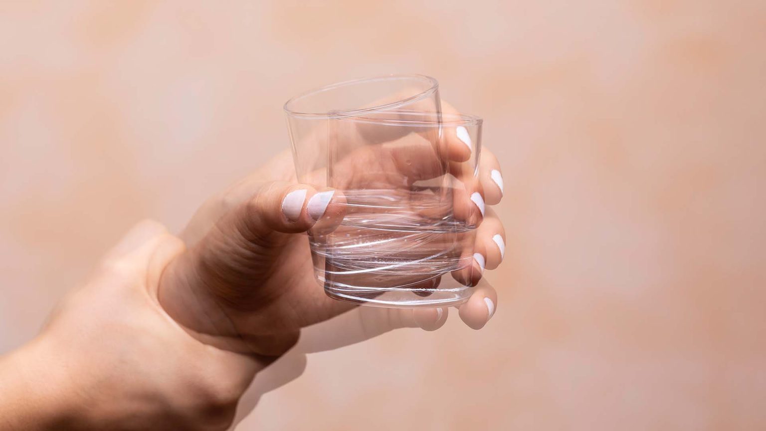 Hand shaking while holding drinking glass.