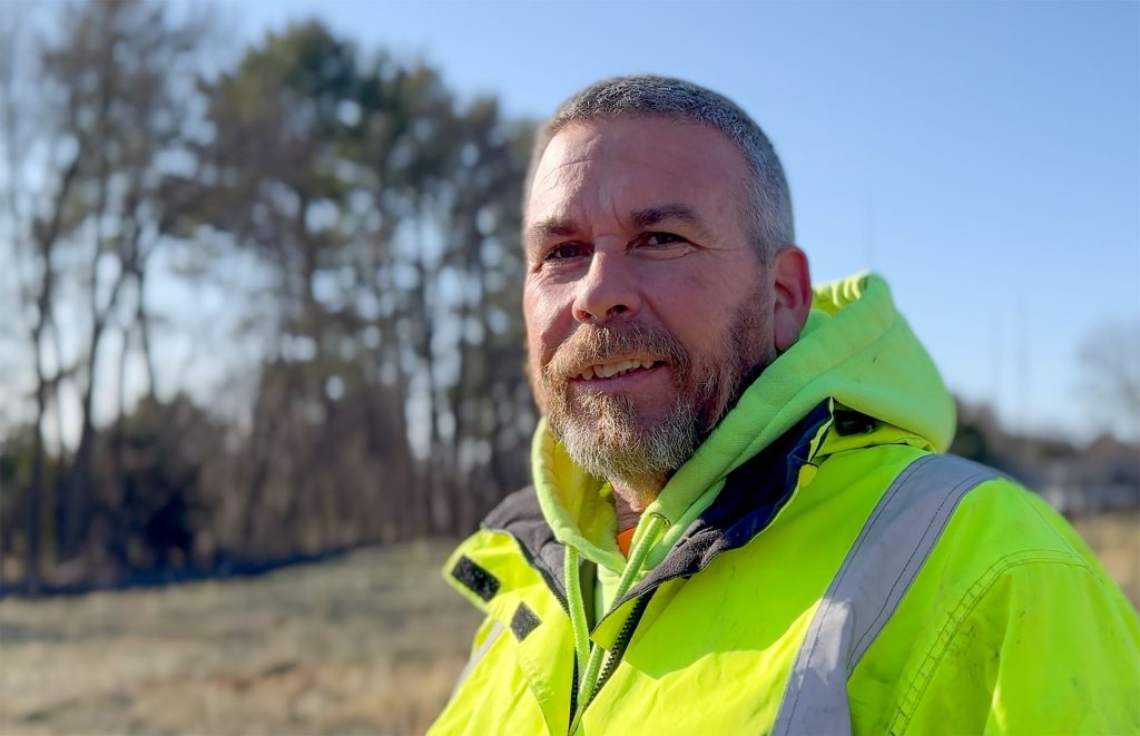 Kevin in hi-vis jacket smiling outdoors.