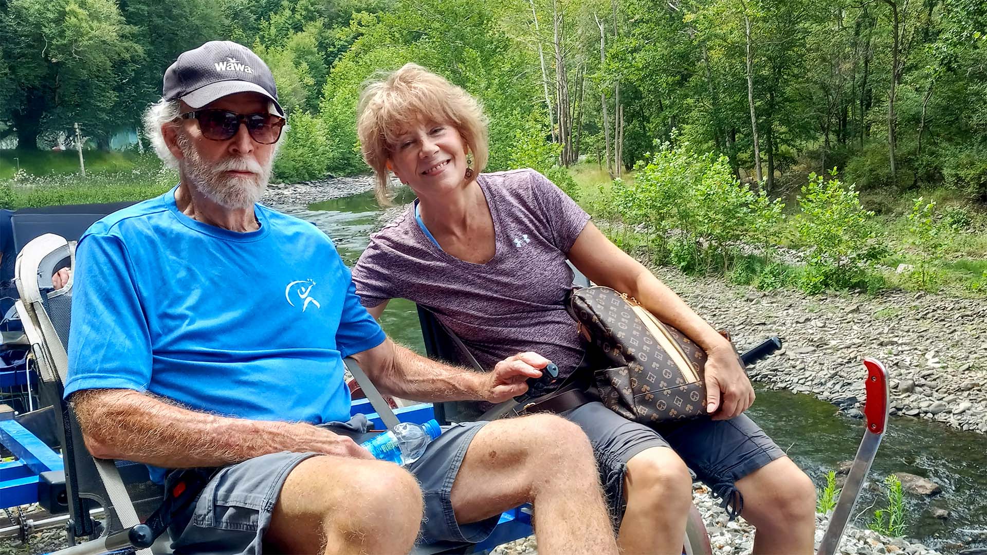 Rick and Val sitting together in a park near a creek.