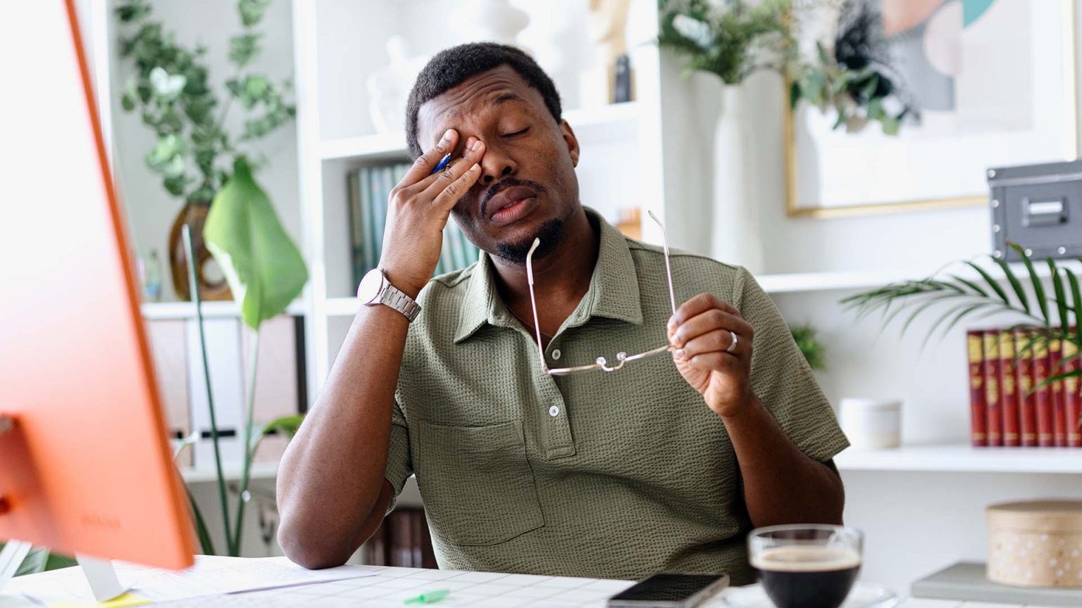 Tired man rubbing eyes in office setting.